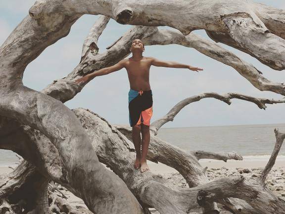 乔治亚州杰基尔岛浮木海滩上的男孩。图片由@qued3point14